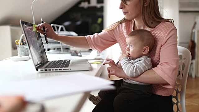 una madre con su bebé estudiando una Maestría por Internet