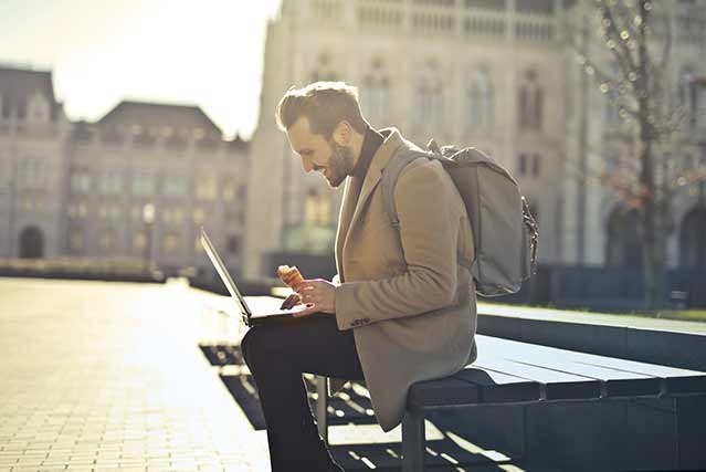 Reciclarse en el trabajo - hombre joven con laptop en un parque estudiando online