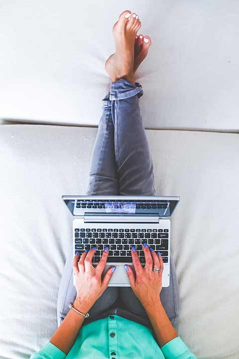 estudiar un posgrado - mujer estudiando un posgrado online con su portátil en la cama
